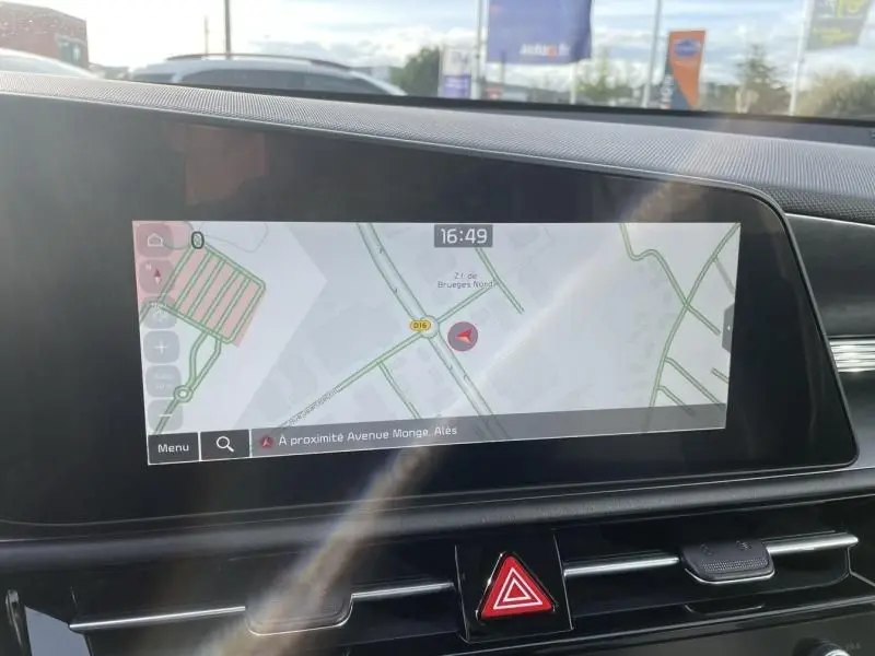 Écran tactile central du Kia Niro 2024 affichant la navigation, avec tableau de bord noir et bouton de signal d’alerte rouge visible.
