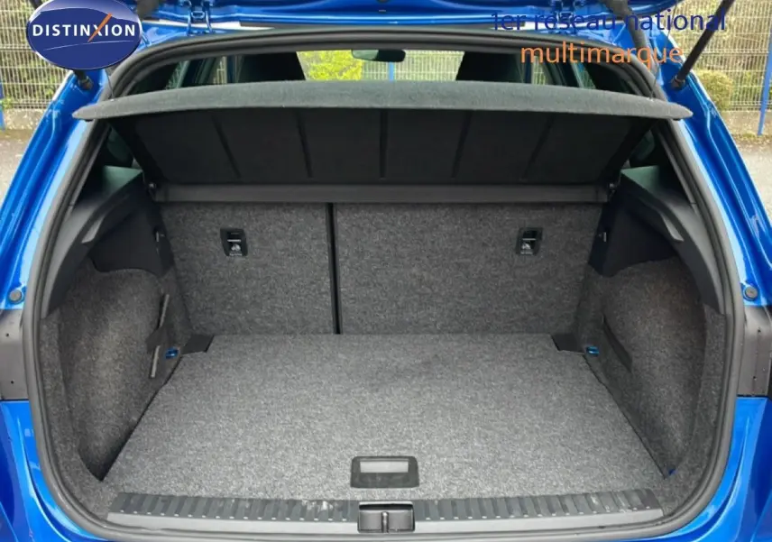 Coffre ouvert vu de l'arrière d'un SEAT Arona bleu saphir métal avec toit blanc, montrant un espace de chargement vide.
