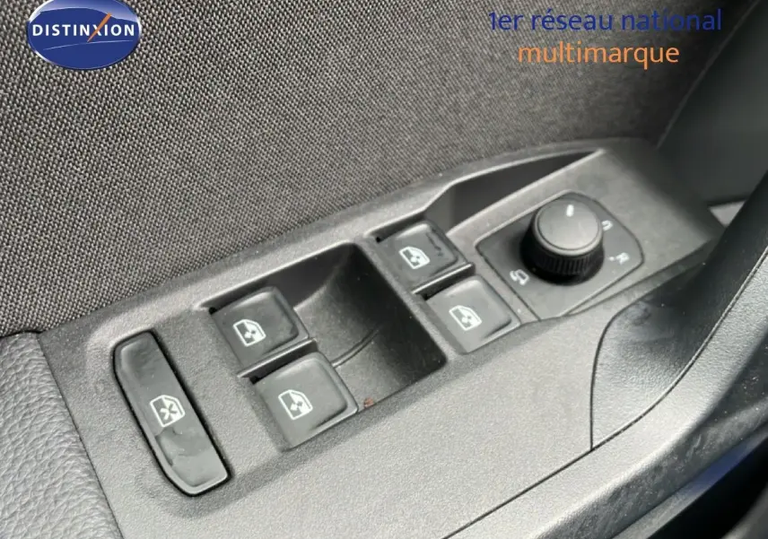 Gros plan sur les commandes des vitres électriques et rétroviseurs côté conducteur du SEAT Arona bleu saphir 2025.