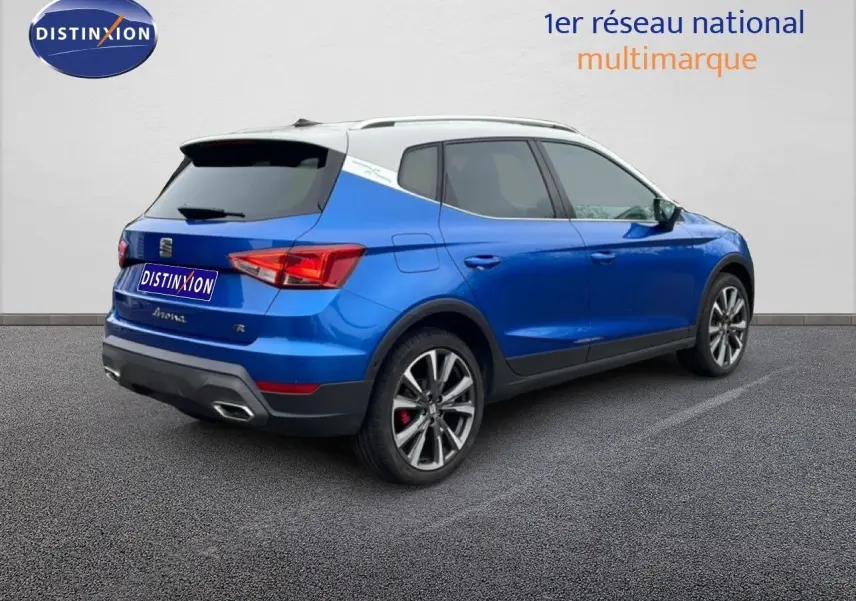 Vue 3/4 arrière droite d’un SEAT Arona bleu saphir métal avec toit blanc, jantes alliage et feux arrière LED.