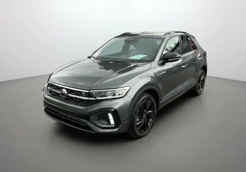 Volkswagen T-Roc gris indium en 3/4 avant droit avec jantes noires et barres de toit noires visibles.