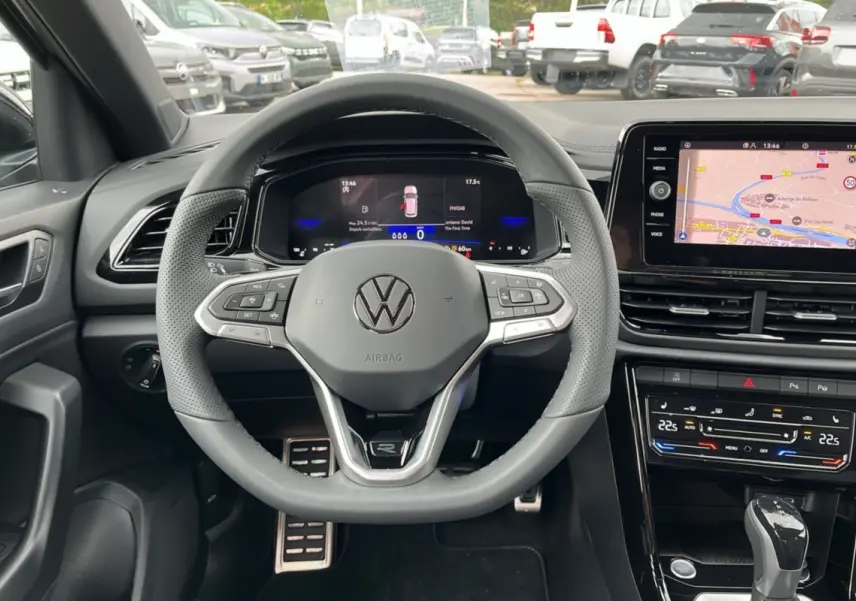 Vue intérieure centrée sur le volant cuir multifonctions du Volkswagen T-Roc gris indium avec tableau de bord digital.