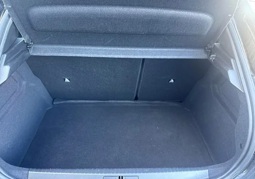Coffre ouvert de la Peugeot 208 1.2 100 Allure noir, vue intérieure montrant l'espace de rangement vide.