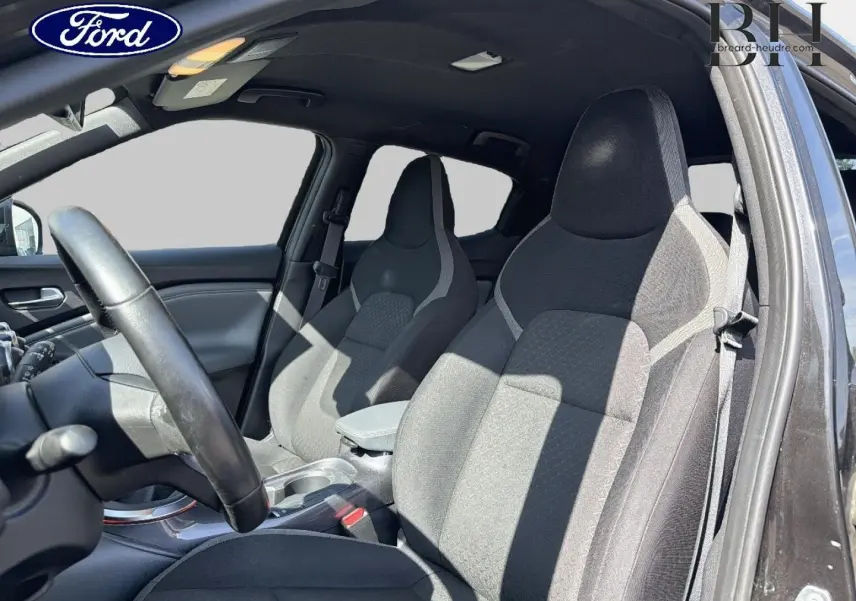 Vue intérieure côté conducteur du Nissan Juke 2020 noir métallisé, mettant en valeur les sièges avant en tissu gris foncé.