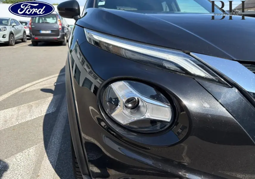 Gros plan sur le phare avant droit du Nissan Juke noir métallisé, soulignant son design moderne et ses lignes épurées.