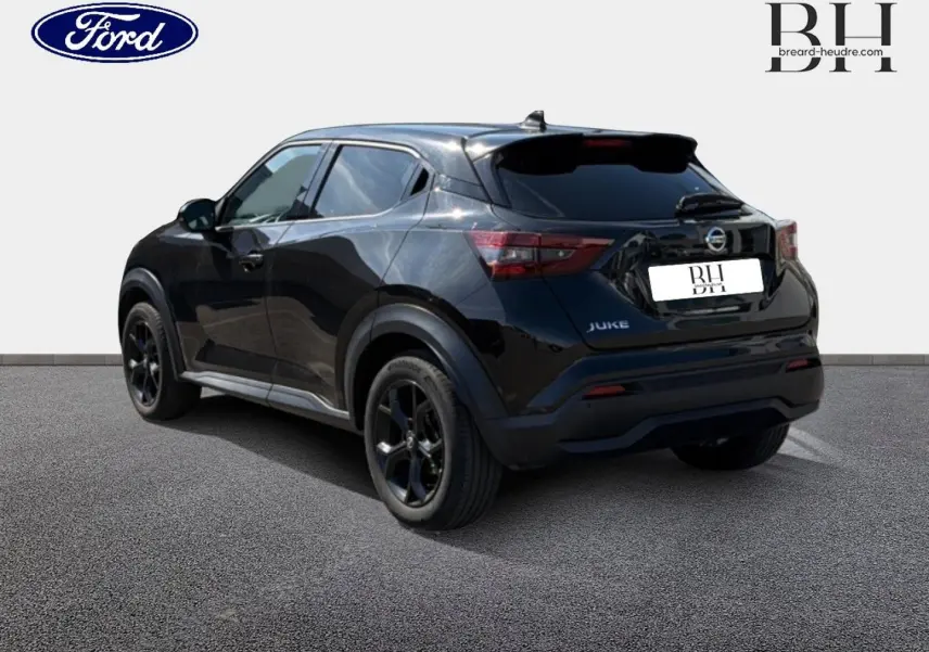 Vue 3/4 arrière droite du Nissan Juke noir métallisé avec jantes alu noires sur sol gris.