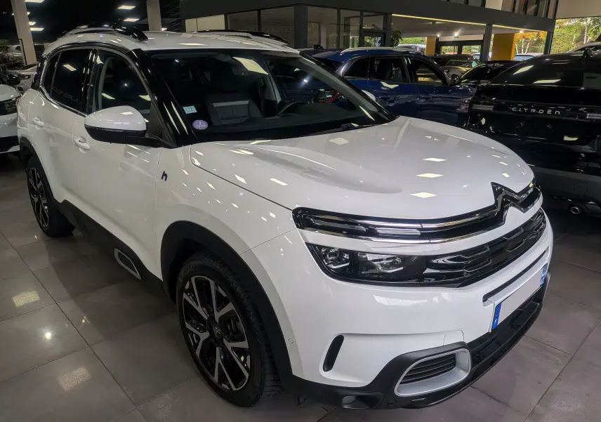 Citroën C5 Aircross hybride rechargeable blanc glacier vue 3/4 avant en intérieur avec jantes noires bicolores.