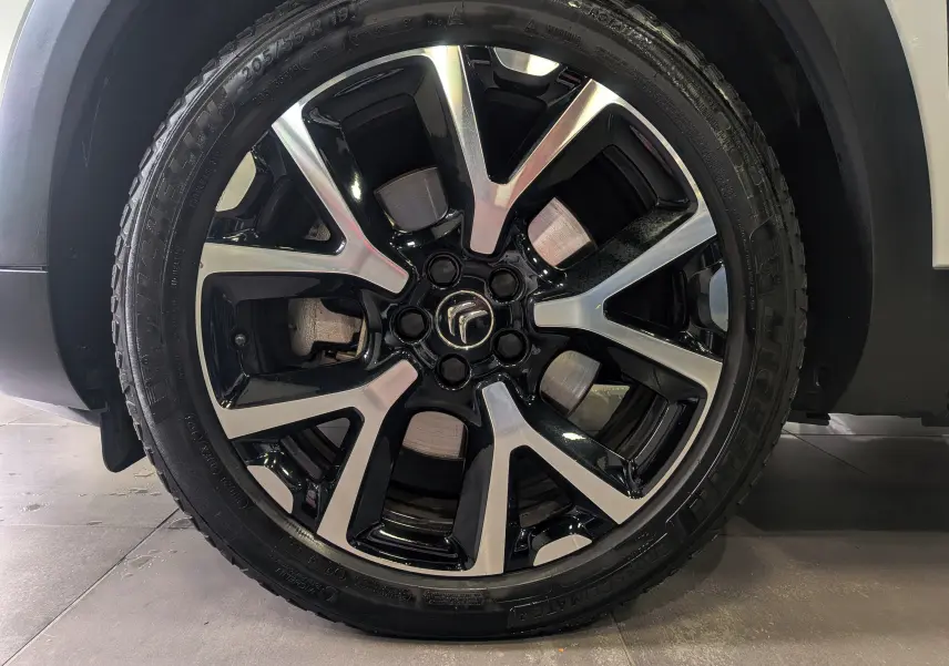 Gros plan sur la jante noire et argentée du côté gauche d'un Citroën C5 Aircross blanc glacier hybride rechargeable.