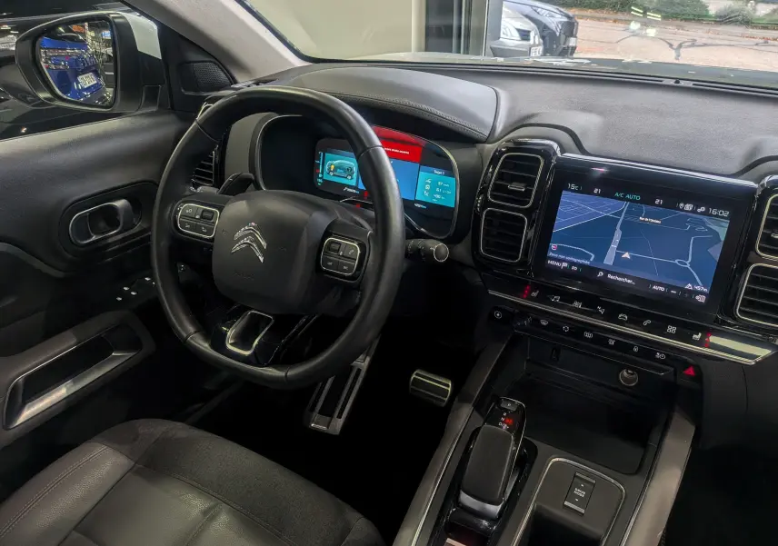 Intérieur noir du Citroën C5 Aircross hybride rechargeable 2021, vue du poste de conduite avec tableau de bord numérique et écran tactile GPS.