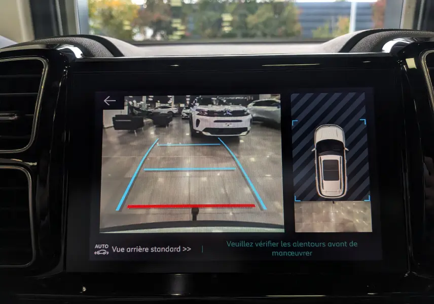 Affichage caméra de recul montrant un Citroën C5 Aircross blanc Glacier vu de l'arrière dans un garage lumineux.