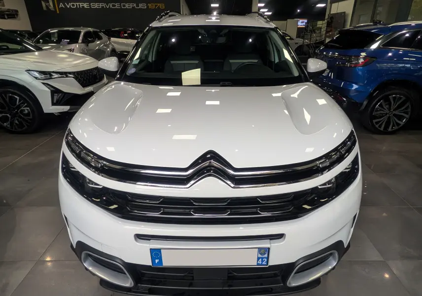 Vue de face du Citroën C5 Aircross hybride rechargeable blanc glacier dans un showroom lumineux.