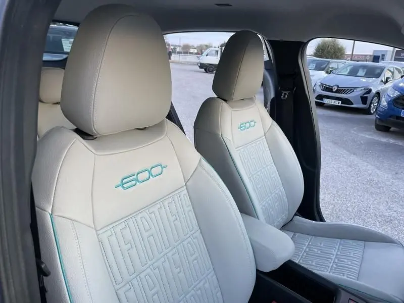 Vue intérieure rapprochée des sièges avant beige de la FIAT 600 Hybrid 2025 avec logo 600 brodé en bleu clair.