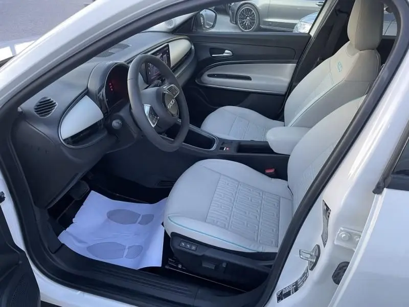 Vue intérieure côté conducteur de la FIAT 600 blanche 2025, sièges clairs avec motifs et tableau de bord moderne.