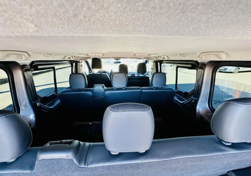 Vue intérieure arrière du Nissan NV300 Combi gris, montrant les sièges en tissu noir sur trois rangées.