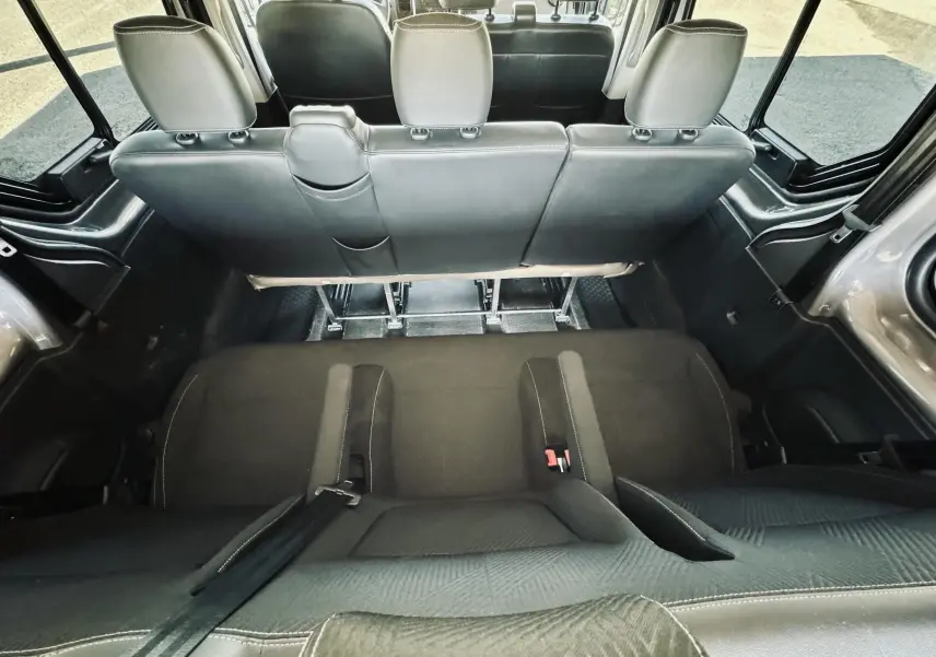 Vue intérieure arrière du Nissan NV300 Combi gris, montrant les sièges en tissu noir et la configuration 9 places.