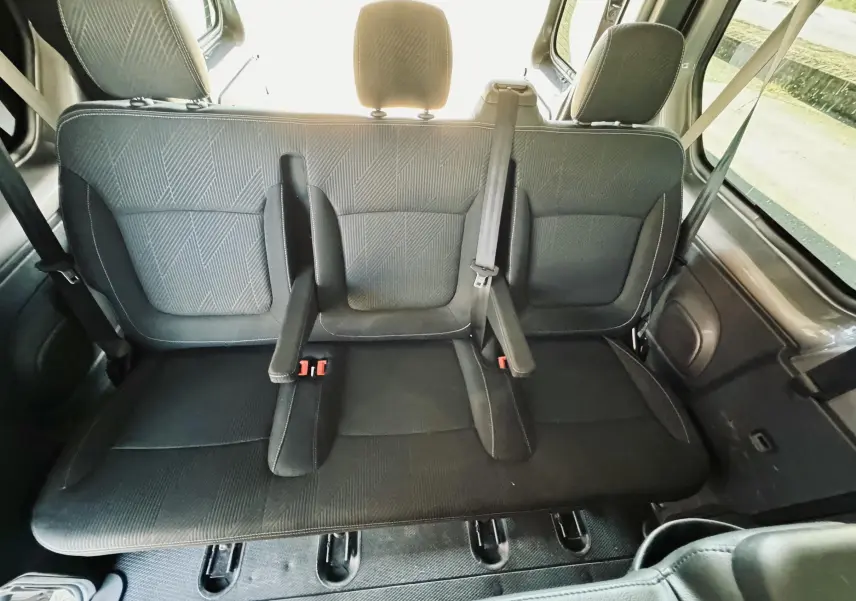 Vue intérieure arrière du siège central gris foncé avec appuie-têtes et ceintures de sécurité du Nissan NV300 Combi.