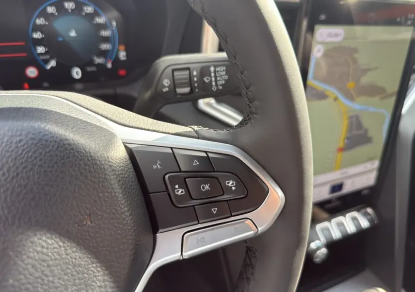 Gros plan sur le volant cuir noir multifonctions et le tableau de bord digital avec navigation du Volkswagen Amarok 2026.