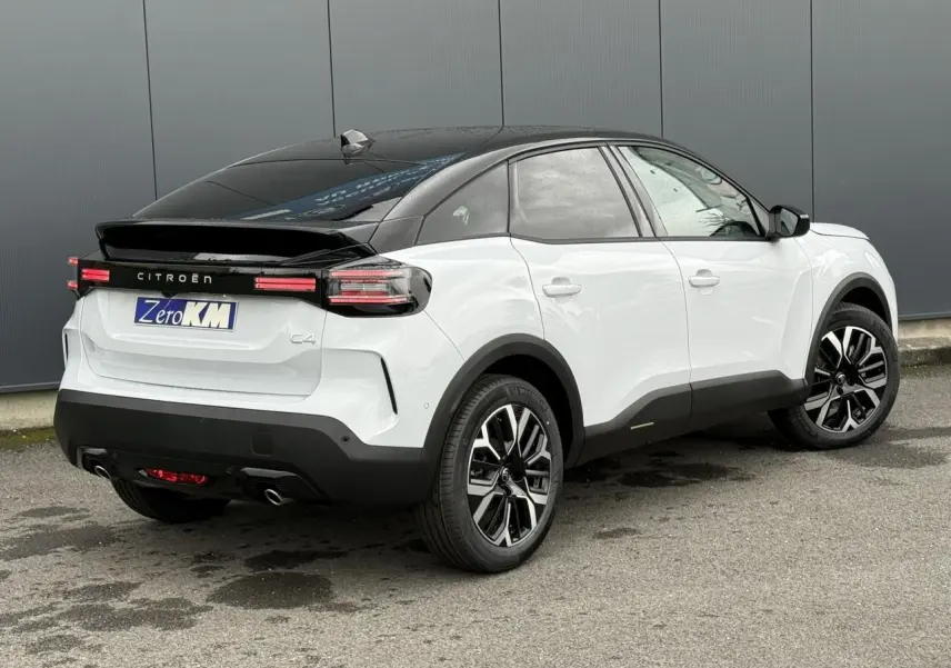 Citroën C4 hybride blanc Okénite avec toit noir, vue 3/4 arrière côté droit, jantes alliage 18 pouces.