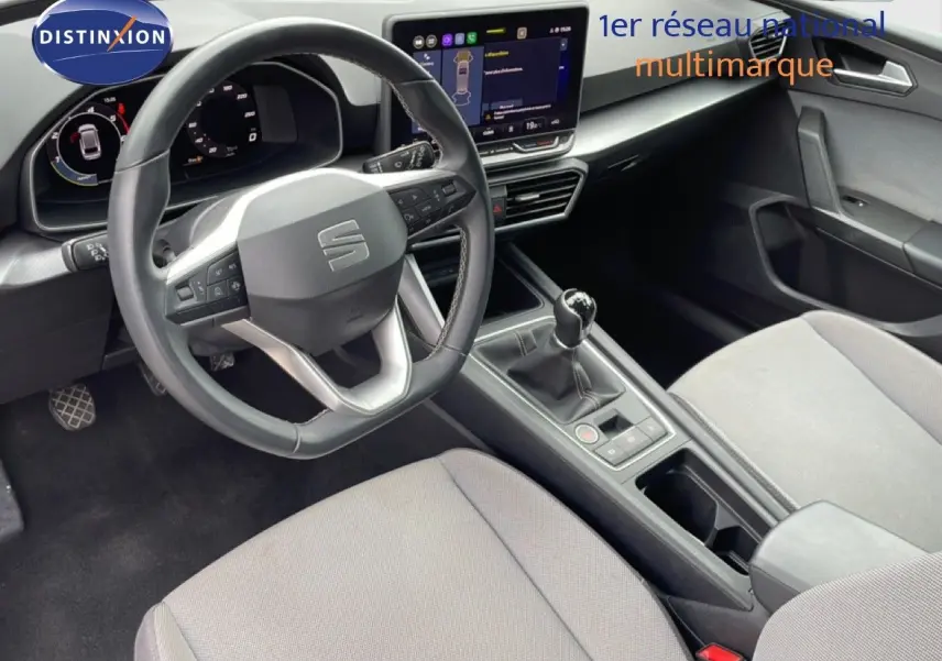 Vue intérieure avant du SEAT LEON ST 2.0 TDI 115CH STYLE XL, montrant volant cuir, tableau de bord digital et sièges tissu gris clair.