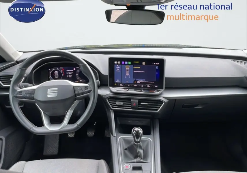 Vue intérieure frontale du tableau de bord et volant gris foncé de la SEAT LEON ST 2025 avec écran tactile et boîte manuelle.