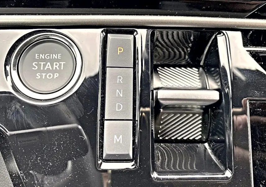 Gros plan sur la console centrale noire brillante du Peugeot 3008 2025 avec bouton start/stop et commandes de boîte auto.