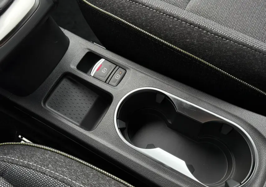 Gros plan sur la console centrale noire du Renault Captur 2025 avec porte-gobelets et frein à main électrique.