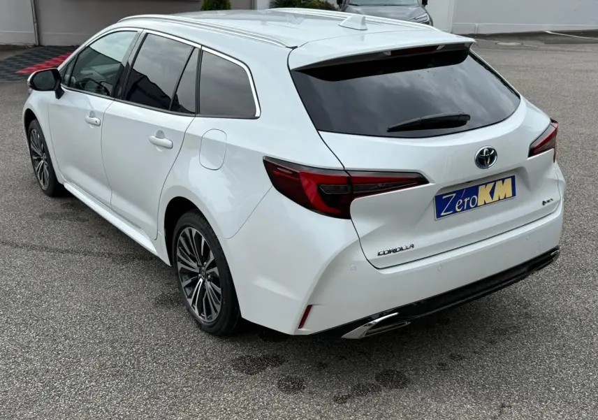 Toyota Corolla Touring Sport blanc lunaire nacré vue 3/4 arrière droit avec vitres teintées et jantes alliage noires.
