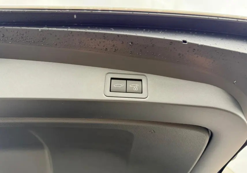 Boutons de commande d'ouverture et de verrouillage du hayon sur le coffre d'une Toyota Corolla Touring Sport blanche nacrée.