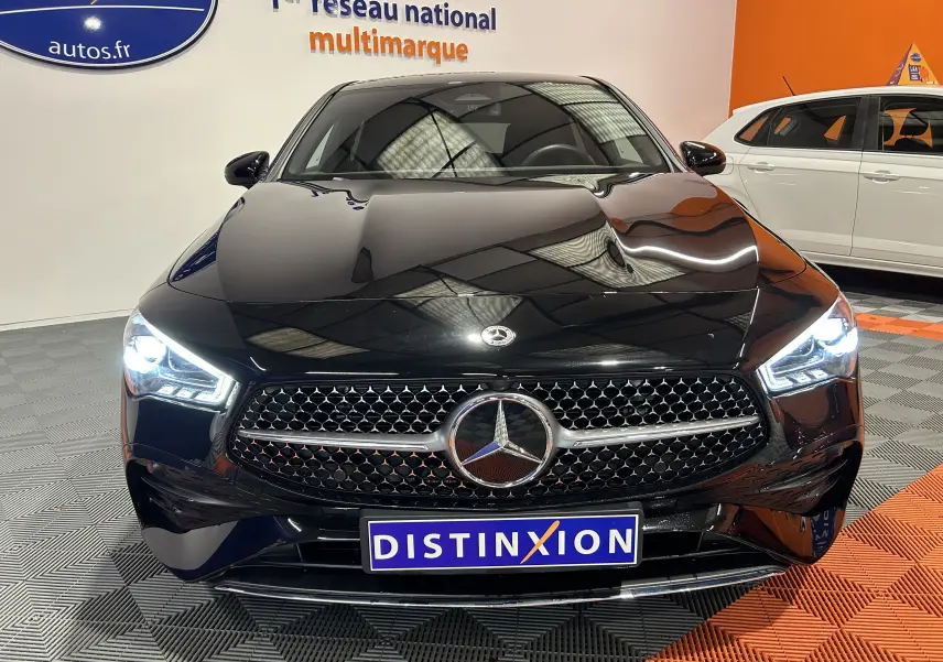 Vue frontale d'une Mercedes Classe CLA Shooting Brake II 200D AMG noire métallisée avec phares LED allumés en showroom.