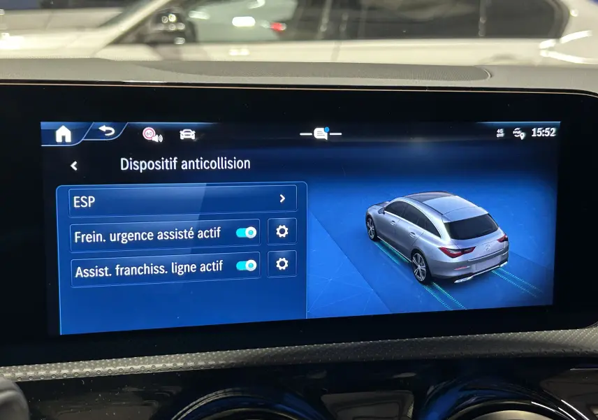 Écran multimédia montrant le menu anticollision avec illustration d'une Mercedes CLA Shooting Brake grise vue en 3/4 arrière.