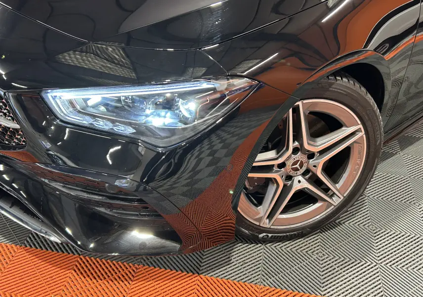 Gros plan sur l'avant droit noir métallisé d'une Mercedes Classe CLA Shooting Brake II 200D AMG avec jante AMG cinq branches.