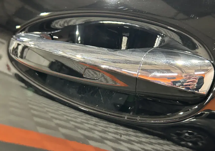 Poignée de porte chromée en gros plan sur le côté gauche d'une Mercedes CLA Shooting Brake noire métallisée.