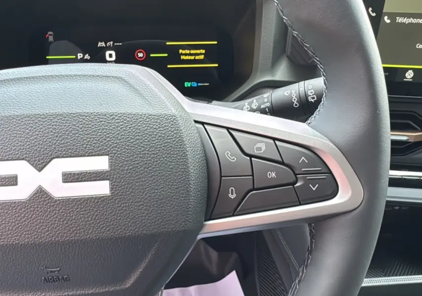 Gros plan sur le volant cuir à commandes multifonctions du Dacia Bigster 2026 avec tableau de bord digital en arrière-plan.