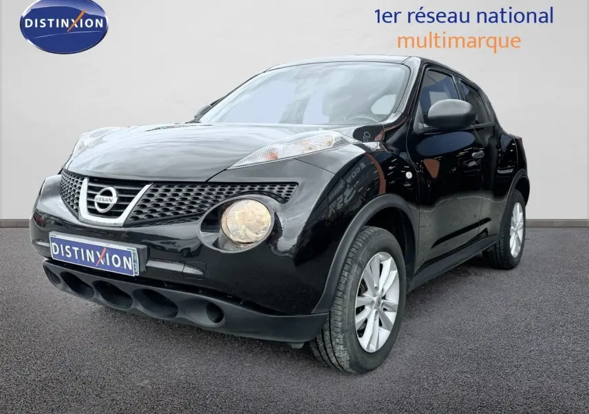 Nissan Juke noir en 3/4 avant droit, avec phares ronds allumés et jantes argentées visibles.