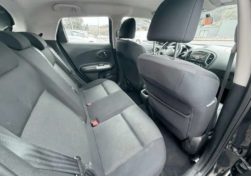 Vue intérieure côté gauche montrant la banquette arrière noire et les sièges avant du Nissan Juke 2012.