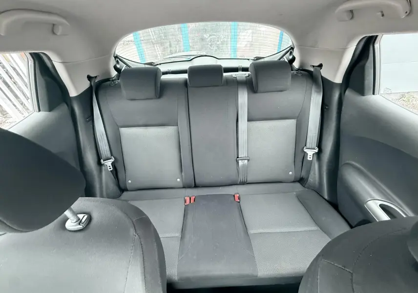Vue intérieure arrière du Nissan Juke 2012 montrant les sièges arrière noirs en tissu avec ceintures de sécurité.