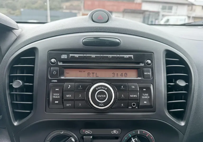 Vue rapprochée de la radio et des commandes de climatisation noires du tableau de bord d’un Nissan Juke 2012.