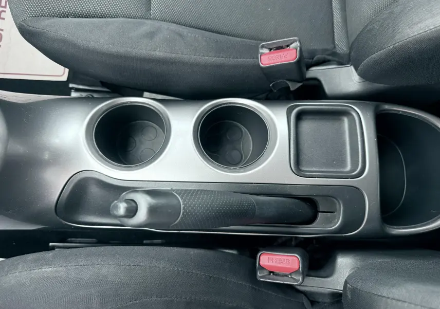 Vue plongeante sur la console centrale noire du Nissan Juke 2012, avec frein à main, porte-gobelets et ceintures de sécurité.