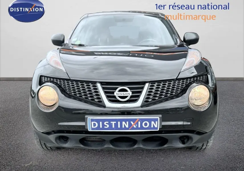 Vue frontale d'un Nissan Juke noir de 2012 avec phares allumés et calandre distinctive en nid d'abeille.