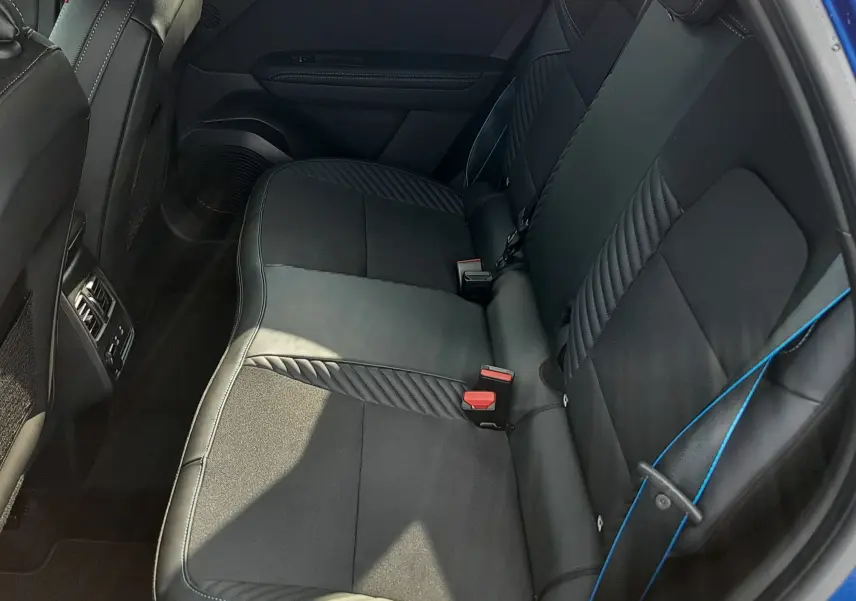 Vue intérieure côté droit des sièges arrière noirs avec surpiqûres bleues du Renault Captur 2024 bleu iron toit noir.