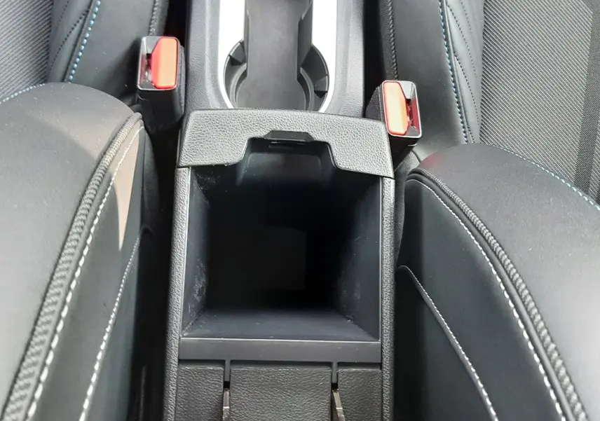 Vue plongeante sur la console centrale noire du Renault Captur 2024, avec porte-gobelets et accoudoirs en tissu noir.