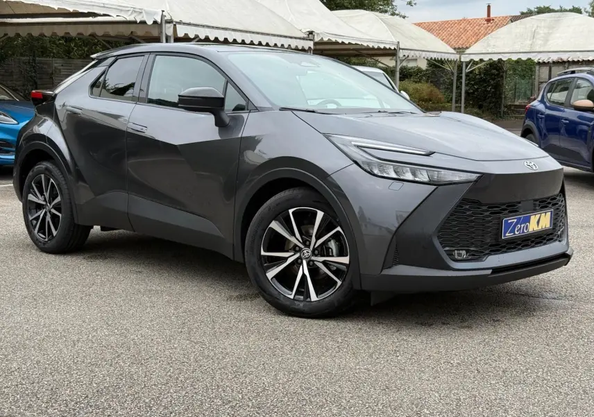 Toyota C-HR 1.8 140CH STYLE gris atlas en 3/4 avant droit, avec jantes alliage et calandre noire distinctive.
