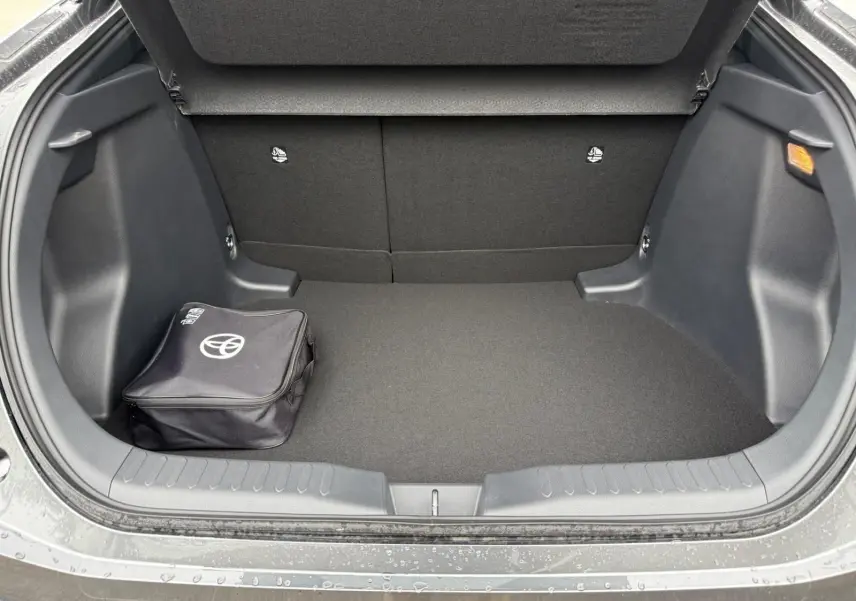 Coffre ouvert d’un Toyota C-HR gris atlas 2025, montrant un espace de chargement propre avec sac Toyota noir.