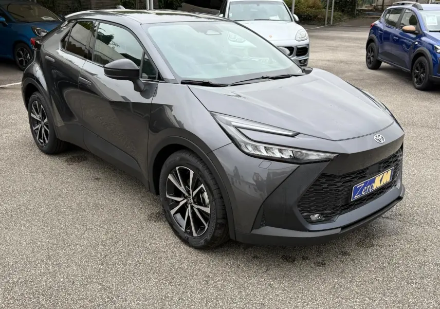 Toyota C-HR 1.8 140CH STYLE gris atlas en vue 3/4 avant droit, avec calandre noire et jantes alliage noires.