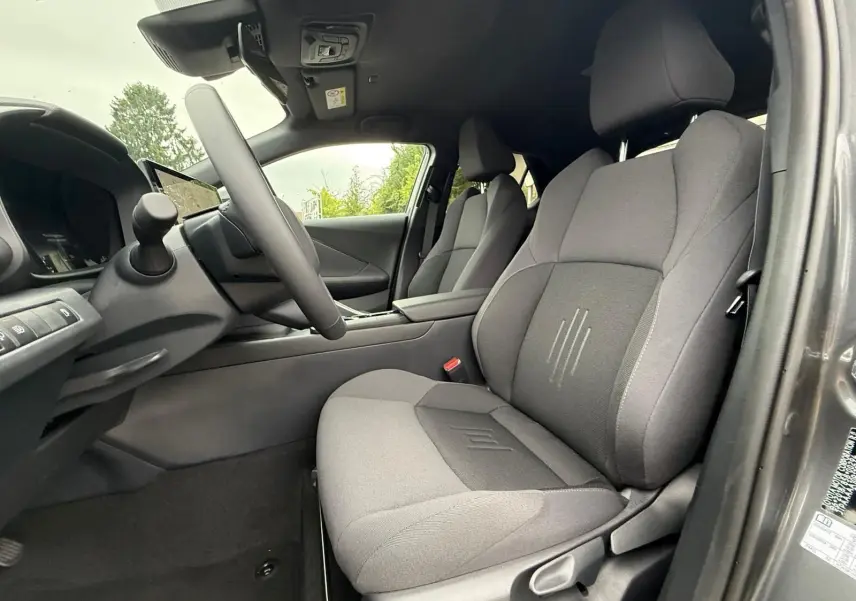 Intérieur du Toyota C-HR 1.8 140CH STYLE 2025, vue côté conducteur sur sièges tissu gris et tableau de bord moderne.