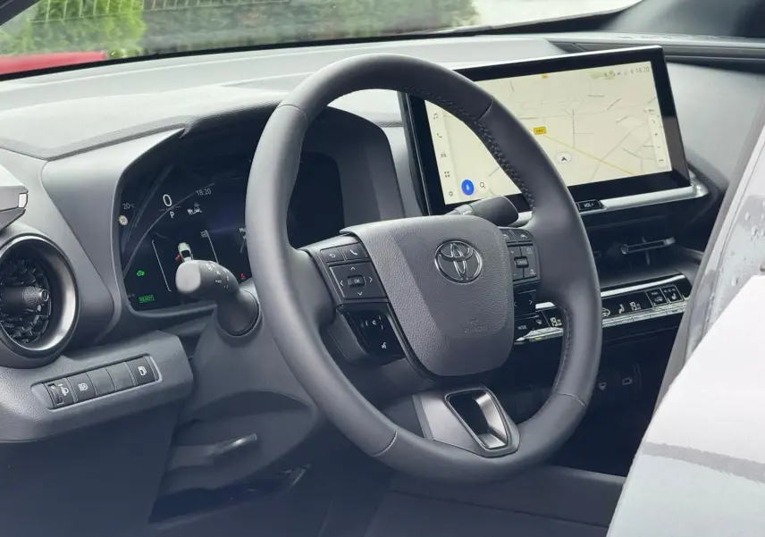 Vue intérieure du tableau de bord du Toyota C-HR gris atlas 2025, avec volant multifonction et écran tactile GPS.