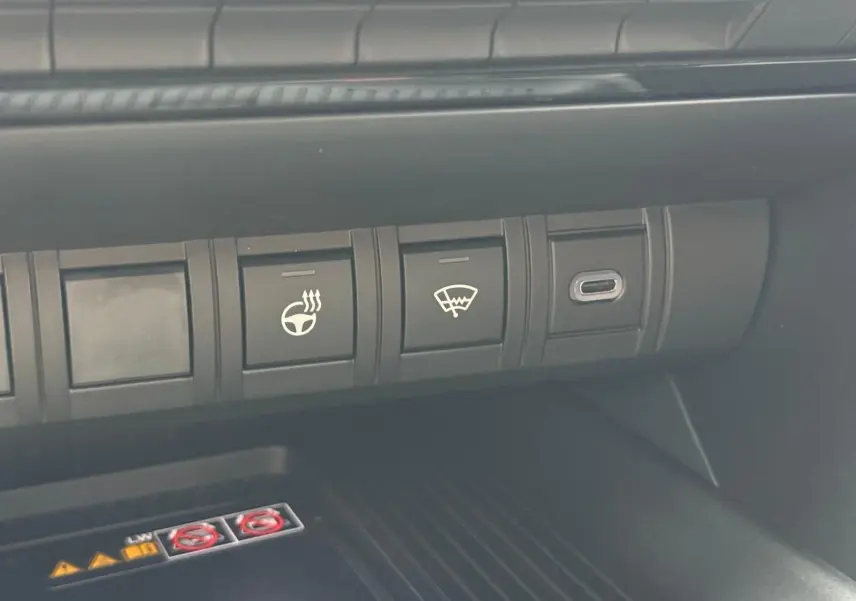 Gros plan sur les commandes du tableau de bord du Toyota C-HR gris atlas, avec bouton de volant chauffant et dégivrage.