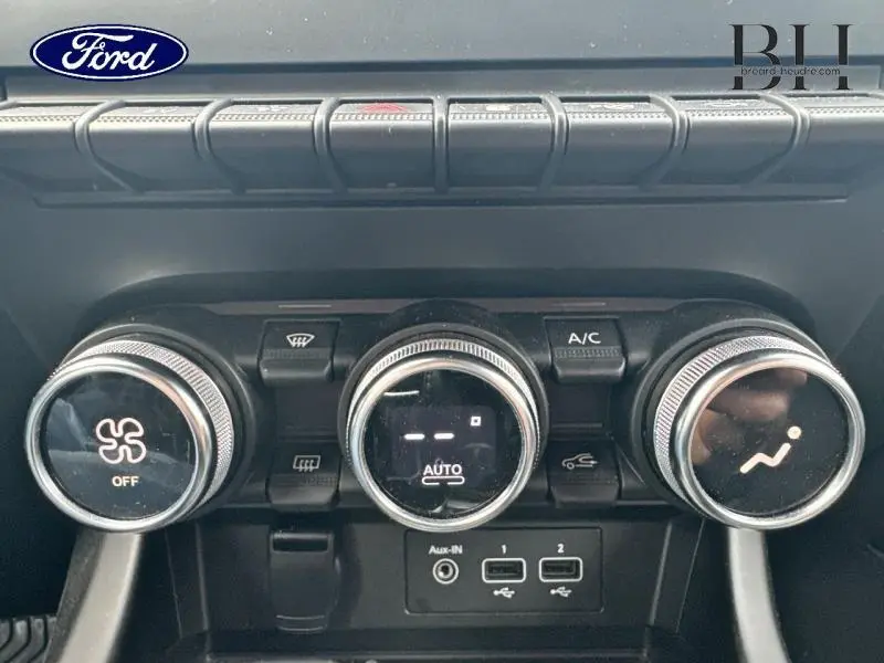 Panneau de commande de climatisation en noir avec trois molettes rondes sur Renault Arkana Bleu Zanzibar vue intérieure.