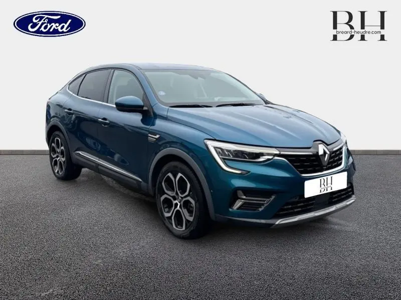 Renault Arkana Bleu Zanzibar en 3/4 avant droit, SUV hybride avec jantes alu et signature lumineuse LED distinctive.