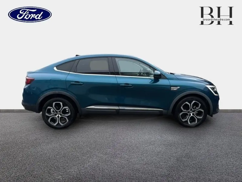 Profil côté gauche d'un Renault Arkana 2022 en bleu Zanzibar avec jantes alliage et lignes chromées élégantes.